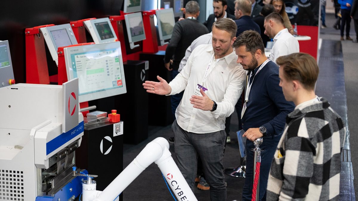 EuroBLECH fuarında bir makine ve robot sistemi başında teknik görüşme yapan ziyaretçiler